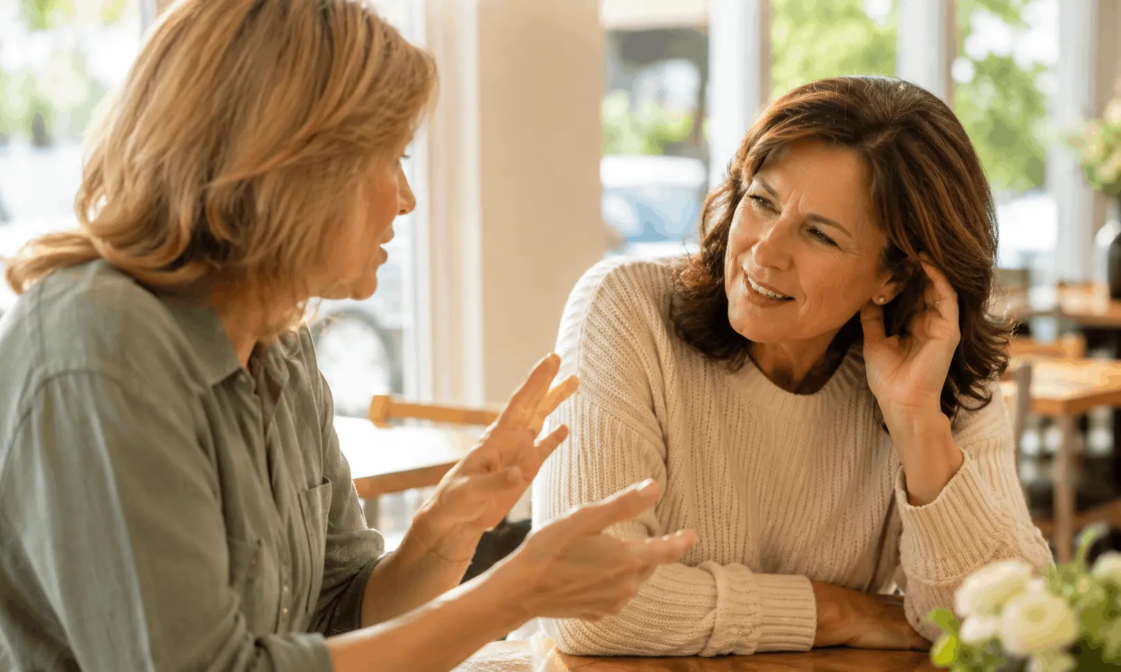 Two women in their 50s having a conversation at a cafe — the importance of being able to hear clearly